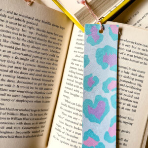 Faux leather bookmark in turquoise and pink with tassel, placed on open book – perfect graduation or teacher gift