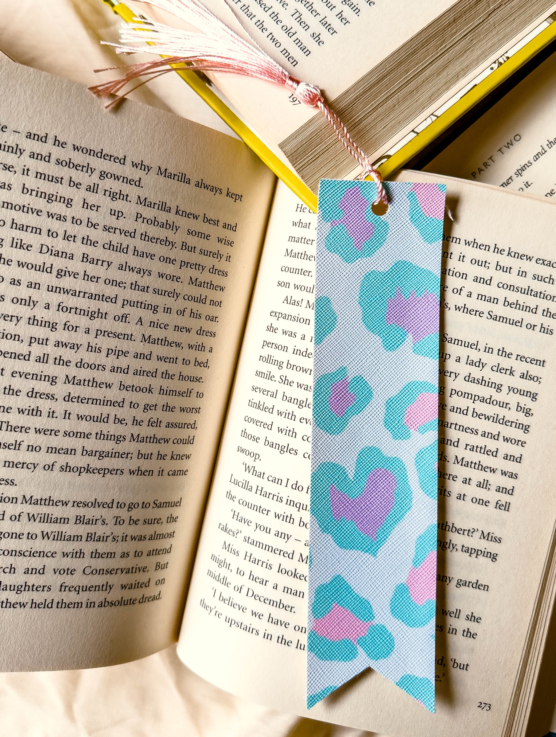 Faux leather bookmark in turquoise and pink with tassel, placed on open book – perfect graduation or teacher gift