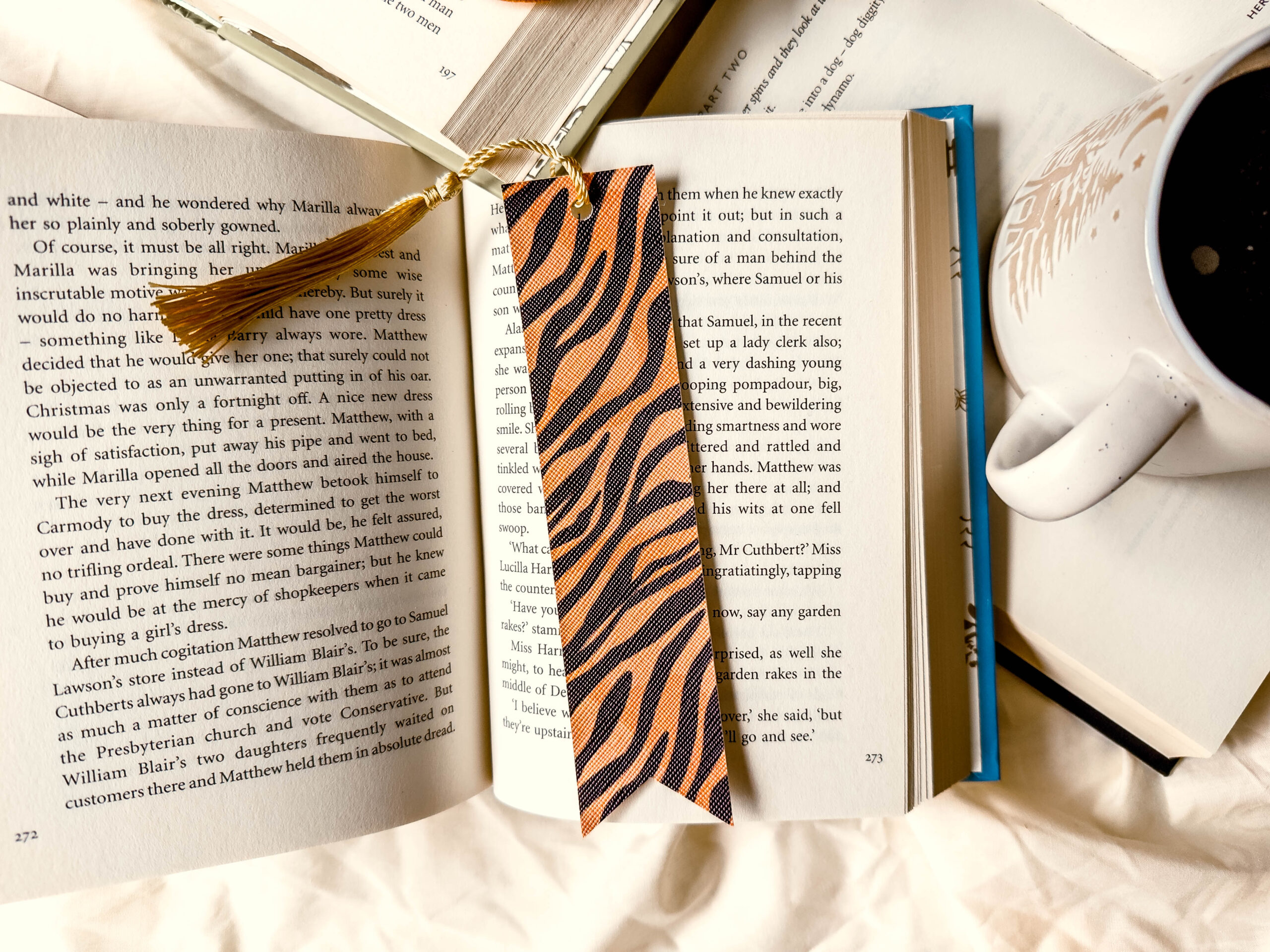 Handmade faux leather bookmark with tiger print and black tassel on white background.